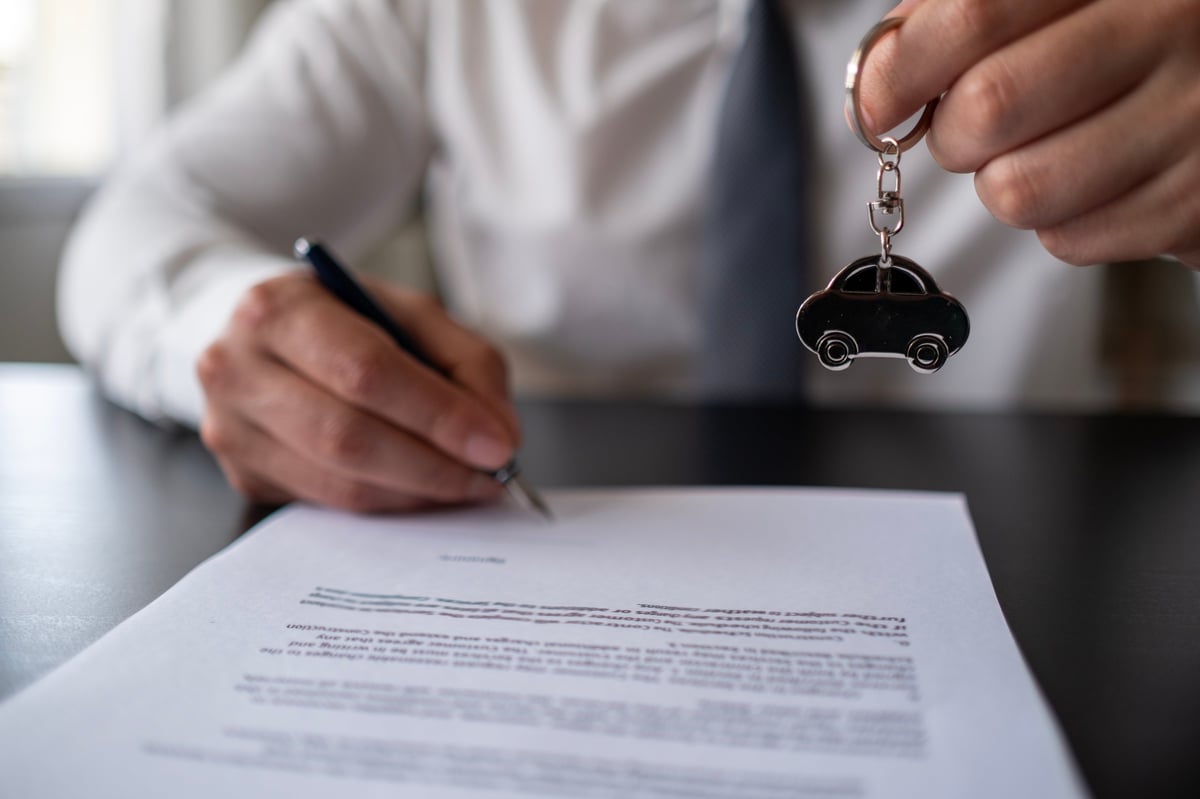 Car dealership handover — salesman handing keys to a customer after a successful deal, representing the premium experience of Islamic car finance